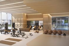 there are many exercise equipment in this large room with lots of glass doors on the walls