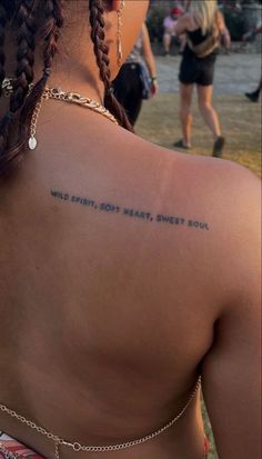 the back of a woman's shoulder with words written on it and people in the background