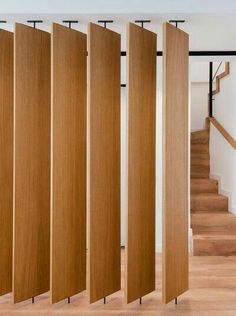 a room divider made out of wood in front of stairs and wooden flooring