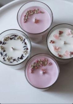 four small candles with flowers on them sitting on a white plate next to each other
