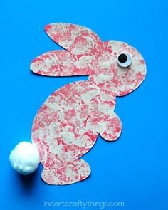 an easter bunny craft made out of paper and cotton balls on a blue background with the words happy easter written across it