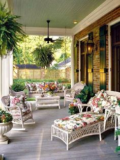 a porch with white wicker furniture and potted plants on the front porch area