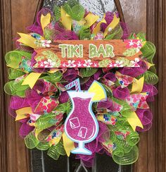 the front door is decorated with colorful deco mesh wreaths and an orange sign that says tin bar