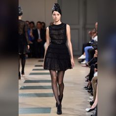 a model walks down the runway in a black dress