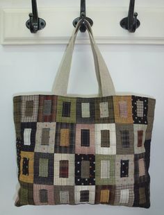 a multicolored patchwork tote bag hanging from a hook on a wall