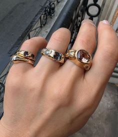 a person's hand with three different rings on it and one is holding the other
