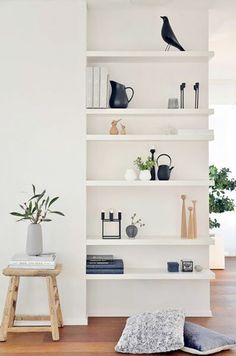a white shelf with some plants on top of it and an image of a bird