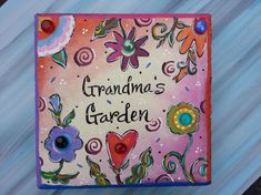 a painted sign that says grandma's garden with flowers and swirls on it