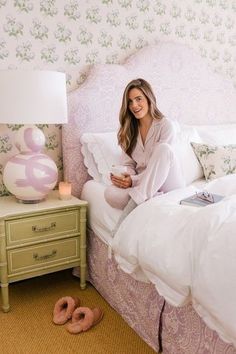 a woman sitting on top of a bed next to a night stand