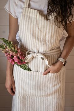 a woman wearing an apron holding a bouquet of flowers