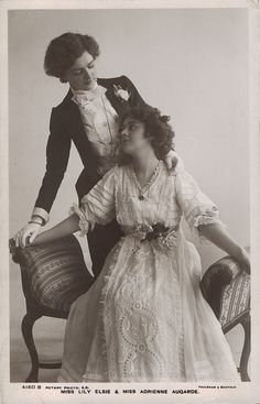 an old fashion photo of two women sitting on a chair, one wearing a dress