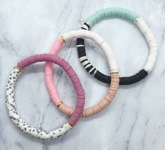 three different colored bracelets sitting on top of a marble counter