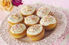 cupcakes with white frosting and sprinkles on a plate
