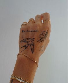 a woman's arm with tattoos on it and a bird tattoo on the wrist