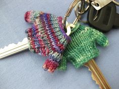 a knitted mitten keychain sitting next to a pair of keys