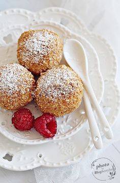 three powdered sugar muffins on a white plate with raspberries