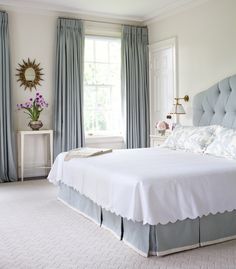 a bedroom with blue curtains and white bedding