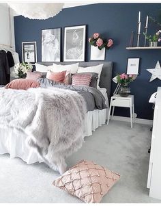 a bedroom with blue walls and white carpeted flooring is decorated in pink and grey tones