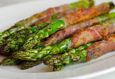 asparagus wrapped in bacon and served on a white plate with colorful geometric background