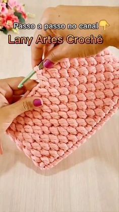 two hands holding a pink crochet purse with text that reads, passo a passo no canal lany aries croches