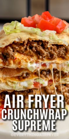 an air fryer crunchwrap supreme stacked on top of each other with tomatoes and lettuce