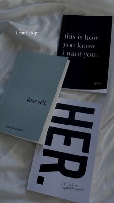 three books laying on top of a bed next to each other with writing on them