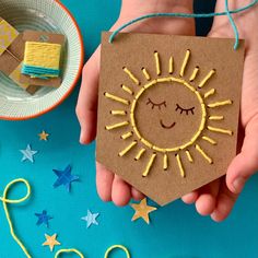 a hand holding a piece of cardboard with a sun on it and stars around it