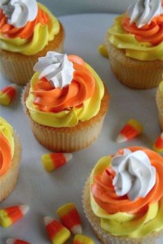 cupcakes with white frosting and candy corn on the top are arranged in rows