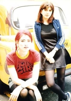 two women sitting next to each other in front of a yellow truck