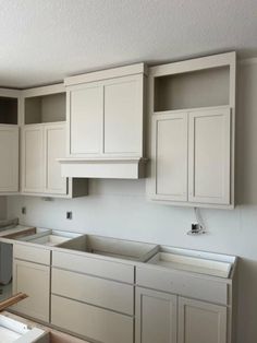 an empty kitchen with white cabinets and drawers