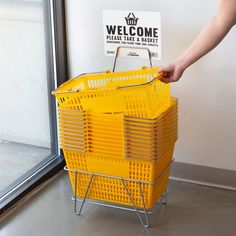 a person holding a yellow shopping basket in front of a welcome sign