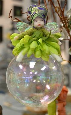 a glass ornament with a little fairy sitting on top of it