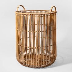 a round wicker basket with handles on the outside and inside, sitting against a white background