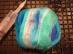 a ball of blue and white yarn next to a syringe on a table