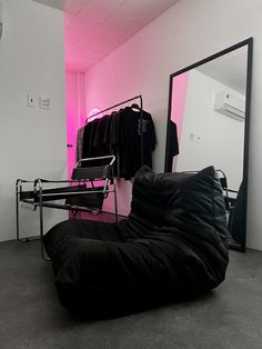 a black bean bag chair sitting in front of a pink wall next to a mirror