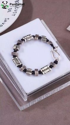 a black and silver beaded bracelet sitting on top of a box