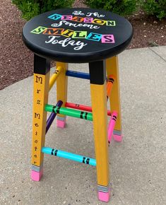 a child's stool made out of crayons with writing on the seat