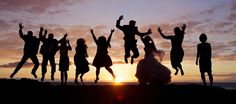 a group of people jumping in the air at sunset