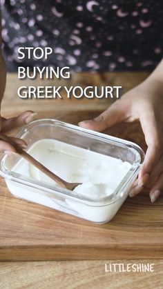 a person holding a wooden spoon over a container of yogurt