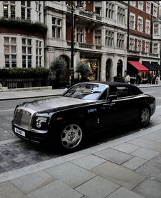 a black rolls royce parked on the side of the road in front of some buildings