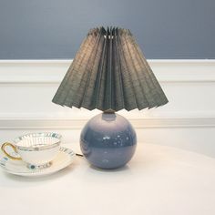 a blue lamp sitting on top of a table next to a cup and saucer