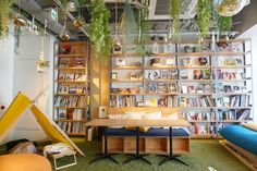 an office with plants hanging from the ceiling and bookshelves on the wall above