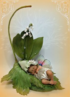a baby sleeping on top of a green leaf next to a white flower and butterfly