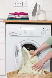 a woman is doing laundry in front of the washing machine with her hand on top of it