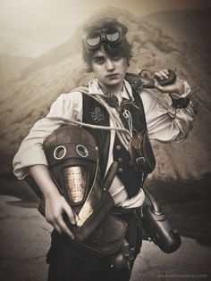 a young man dressed in steampunk clothing and goggles, holding his helmet