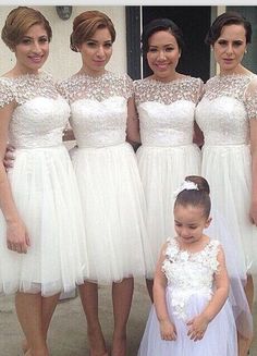 three women in white dresses standing next to each other and one is wearing a flower girl dress