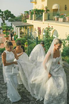 the brides are walking down the steps together in their wedding dresses and veils