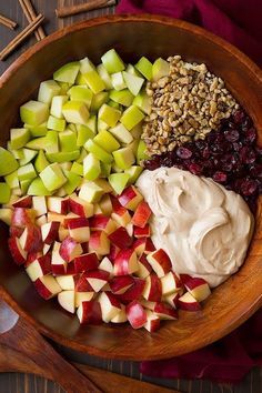 apples, cranberries, nuts and cream in a wooden bowl