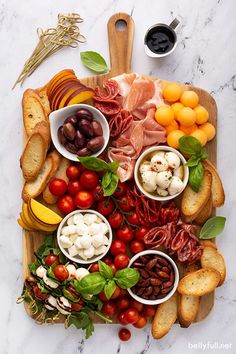 a wooden cutting board topped with different types of food and meats on top of it