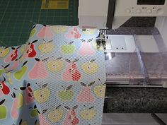 the sewing machine is next to an apple print fabric